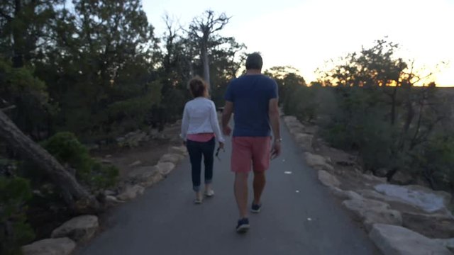A mature couple walking along a paved path at dusk