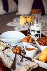 Tray with continental breakfast on hotel bed made of cereals, Cinnamon Balls, chocolate, cakes and a bowl with spoon. Breakfast in bed. Front view