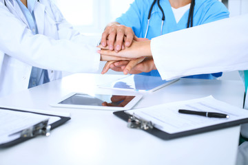 Group of doctors joining hands at meeting. Teamwork and success in medicine