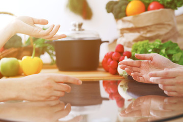 Closeup of human hands cooking in kitchen. Women discuss a menu. Healthy meal, vegetarian food and lifestyle concept