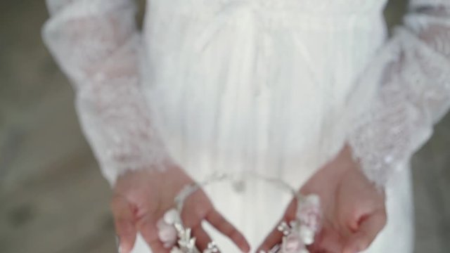 Woman in white dress holding head jewelry wreath