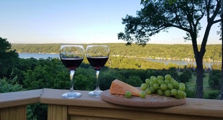 Red Wine in Glasses with Cheese and Grapes Against a Rustic Water View Nearing Dusk; Wines, Wine Tasting,  Life of Leisure, Relaxing Ideas
