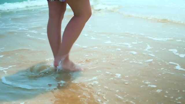 Legs feet caucasian girl walking barefoot wet sand island beach. Slow Motion. Close Up Shot. Colorful