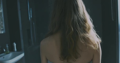 Young woman entering her bathroom in city apartment