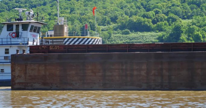 A side profile low angle view of a large coal barge exiting the Newcumberland Lock and Dam on the Ohio River.  	