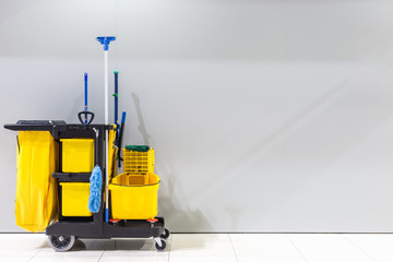 Mop bucket and set of cleaning equipment and sign of men toilet on the wall in the airport