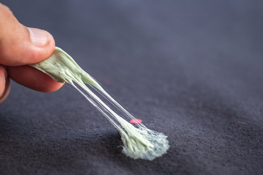 Hand Removing Sticky Chewing Gum From Black Textile Or Clothes