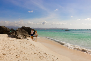 BORACAY, PHILIPPINES - Jan 30, 2018: the guy with the girl is walking along the Diniwid beach and watching the sunset.