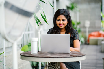 A confident and successful Indian woman (professional or business woman) is sitting and working on...