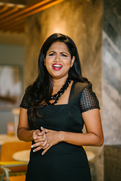 A close up image of a successful and attractive Indian Asian desi woman sitting in the corridor of her office. She lloks worried and stress while posing for her professional head shot photo. 