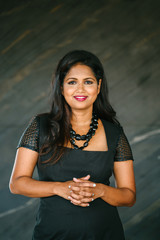 Professional studio portrait of a confident, mature, and successful Indian Asian Desi woman in an elegant black dress.