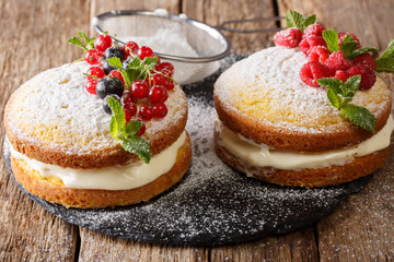 Delicious sandwich Victoria cake with black and red currants, raspberries and mint closeup on the table. horizontal