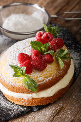 Victoria naked cake decorated with raspberries and mint closeup on a table. vertical