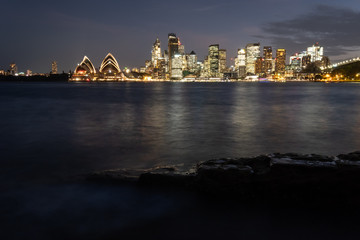 Sydney city lit up in the evening and spilling light over the beautiful Sydney Harbour