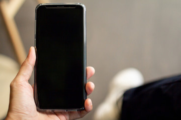 Close up of male hands holding touching mobile phone with blank copy space for your text message in cafe with light Sunset,Vintage tone.Selective focus