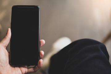 Close up of male hands holding touching mobile phone with blank copy space for your text message in cafe with light Sunset,Vintage tone.Selective focus