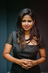 Professional studio portrait of a confident, mature, and successful Indian Asian Desi woman in an elegant black dress.
