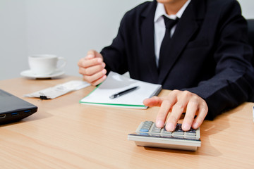 Asian business men in white shirt and black tie, calculate the tax leading to the settlement...