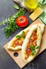 Delicious traditional homemade Greek oval pizza with salami, tomato, onion and cheese.