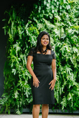 A successful Indian Asian supervisor striking a very elegant pose in front of the camera. She is wearing a beautiful black dress that makes her look very classy.