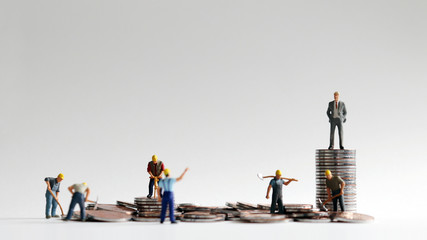 The concept of differences between employer and employee. Coins and miniature people.