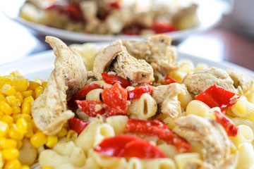 Hot Pasta with Chicken Breast Meat and Vegetables in Large White Plate on Wood Table, Close-Up. Food Background