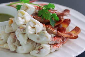 Steamed crab meat prepared for ready to eat with Thai style hot and spicy dipping sauce on white plate put on black granite table in close up view macro style. Delicious homemade seafood concept.