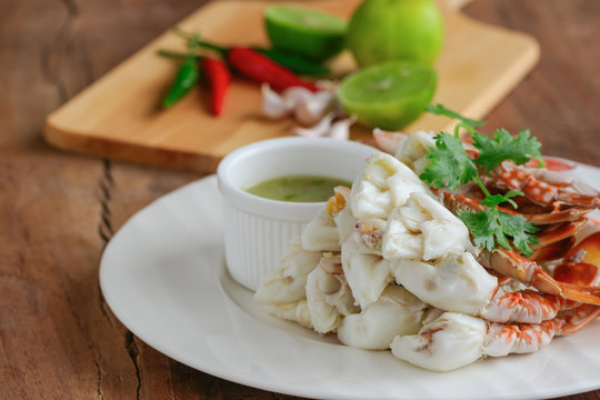 Steamed crab meat prepared for ready to eat with Thai style spicy dipping sauce on white plate put on wood table with copy space for background or wallpaper. Delicious homemade seafood concept.