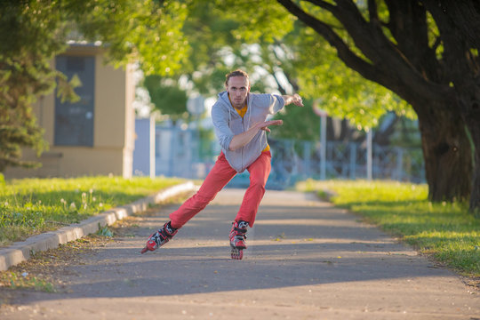 The Guy Quickly Rides On Roller Skates On A Long Road. Sports Driving. With Arms Outstretched At High Speed