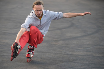 The guy plays the trick on the roller Skates. rides on one leg in a squat.