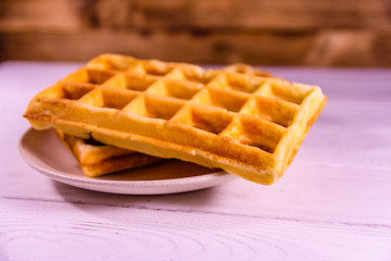 Ceramic plate with belgian waffles on wooden table