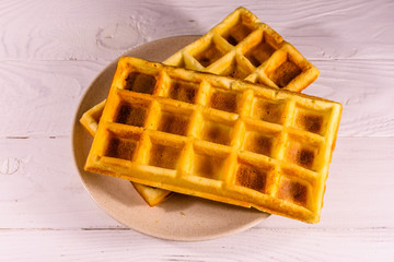 Ceramic plate with belgian waffles on wooden table. Top view