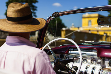 Cuban man driving a vintage car taxi in Havana, Cuba.  Close up of a local taxi driver from the backseat.
