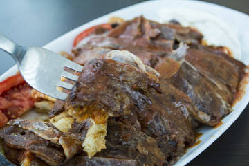 turkish iskender kebab with garnish on a wooden surface at restaurant.