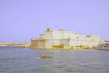 Traditional Maltese dghajsa gondola passing Fort Sant' Angelo
