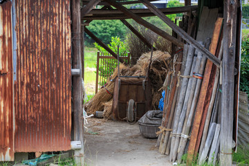 Rusted wheelbarrow with hay and wooden stakes in rustic farming shed