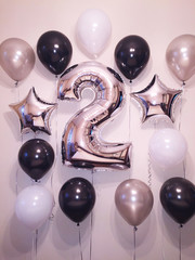 The composition of helium balloons of black, white and silvery colors, as well as silvery stars and...