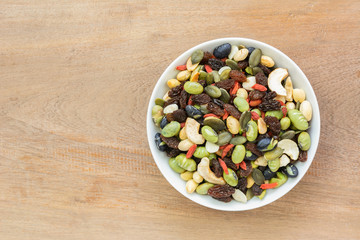 top view of mixed vegetable nuts in a ceramic dish on wooden table with copy space. healthy snack concept.