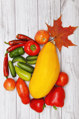 Vegetables and autumn leaves on bright wooden table.