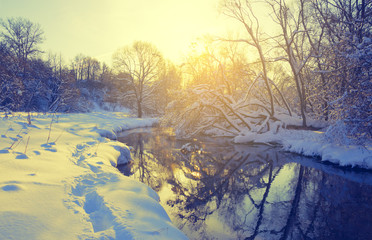 Fantastic winter landscape.Frosty scene with flowing forest river on a sunny morning.Beautiful snow covered trees in the glow of rising sun. 