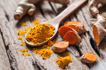 Turmeric powder and turmeric on wooden background