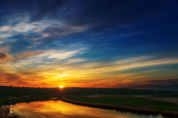 Fototapeta na wymiar good dark sunset in clouds over river