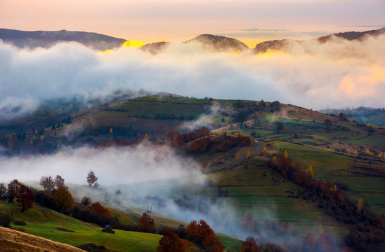 cloud inversion in autumn mountains at dawn. beautiful nature scenery. fog rolling above the rural fields