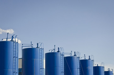 A row of blue water tankers along the street on a sunny day. 