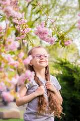 portrait of a six year old girl with glasses in a cherry blossom garden