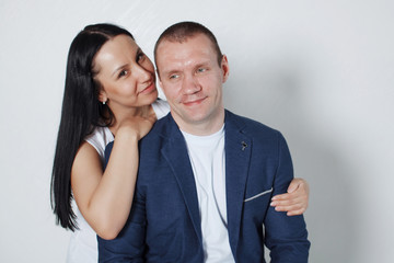 Picture of happy young loving couple standing over grey wall.