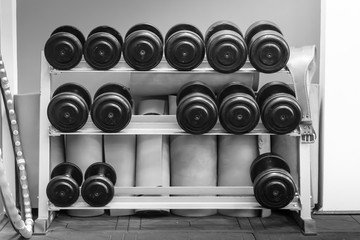 Naklejka na ściany i meble Black dumbbell set. Close up many metal dumbbells on rack ,Weight Training Equipment concept.