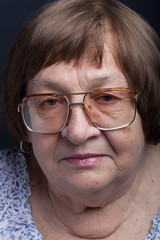 Studio portrait of elderly woman with glasses. Calmness