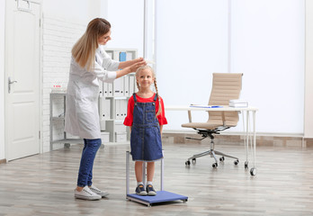 Doctor measuring little girl's height in hospital