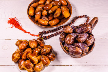 Date fruits and rosary on wooden table